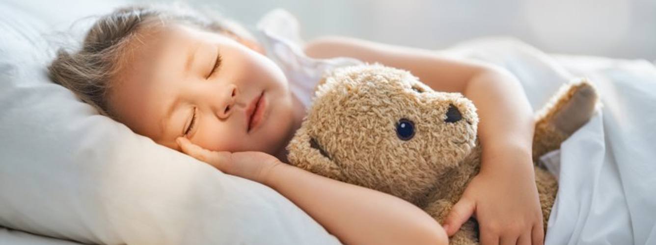 a girl sleeping peacefully with her teddy bear