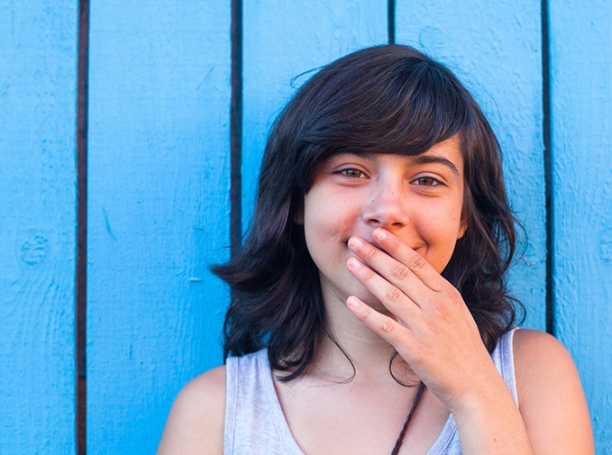 Teen girl using hand to cover her mouth