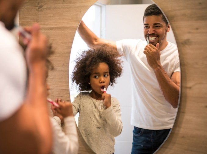 Father and child brushing teeth together