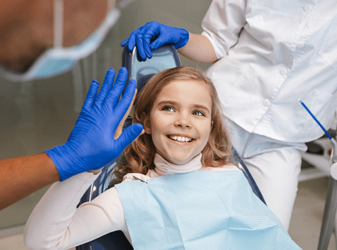 Child high-fiving dentist in dental chair