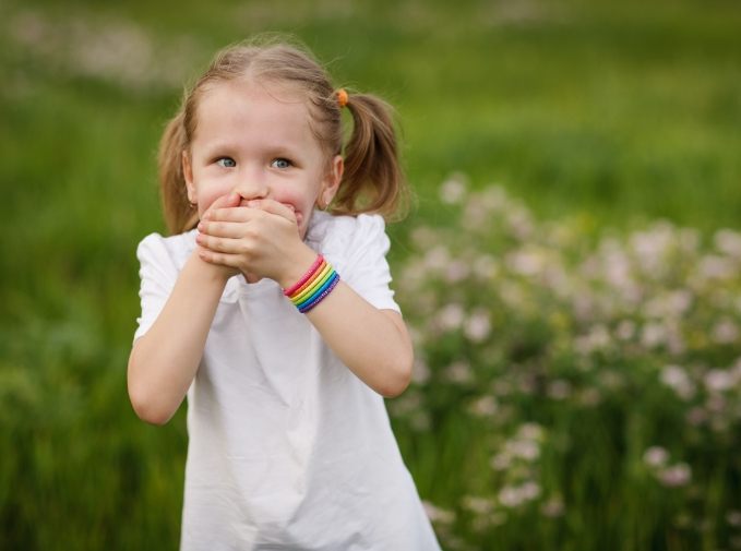 Little girl covering her mouth before emergency dentistry