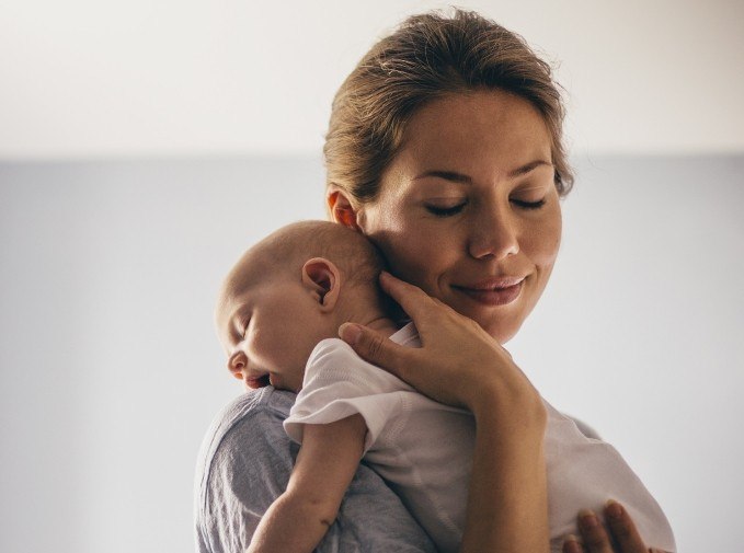 Mother holding sleeping baby with lip and tongue tie