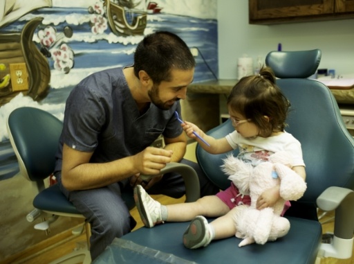 Dentist talking to young child during dentistry for toddlers appointment