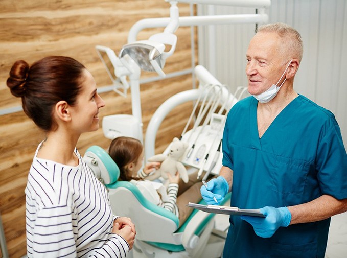 Smiling parent talking to pediatric dentist during child's appointment