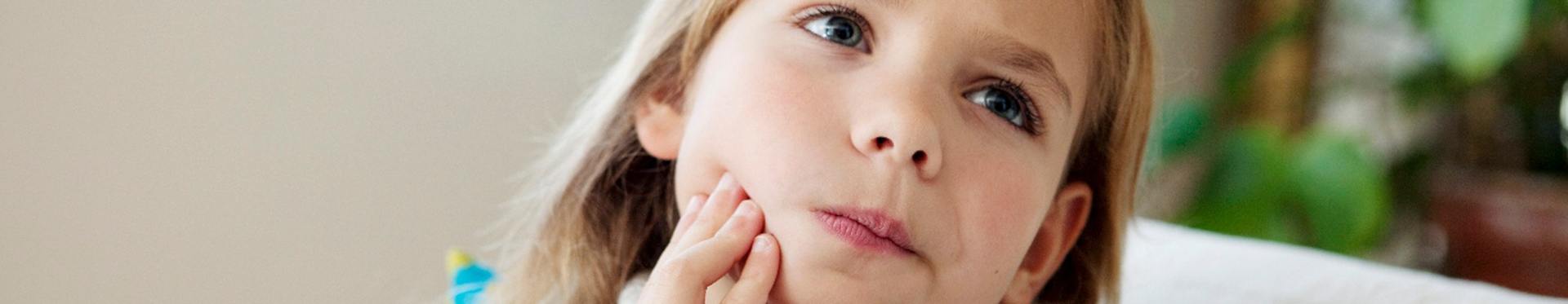 Little girl holding cheek in need of pulp treatment in Inver Grove Heights