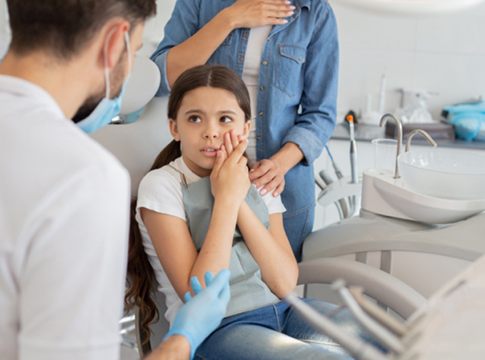 A little girl holding her jaw in pain 