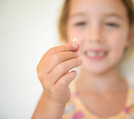A little girl holding an extracted tooth