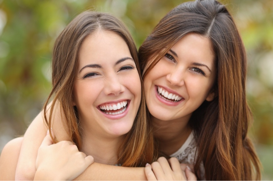 Two young women smiling together after dentistry for teens