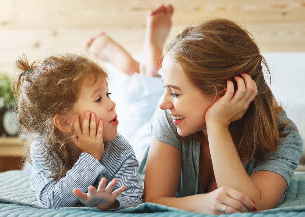 parent and toddler laying on bed together