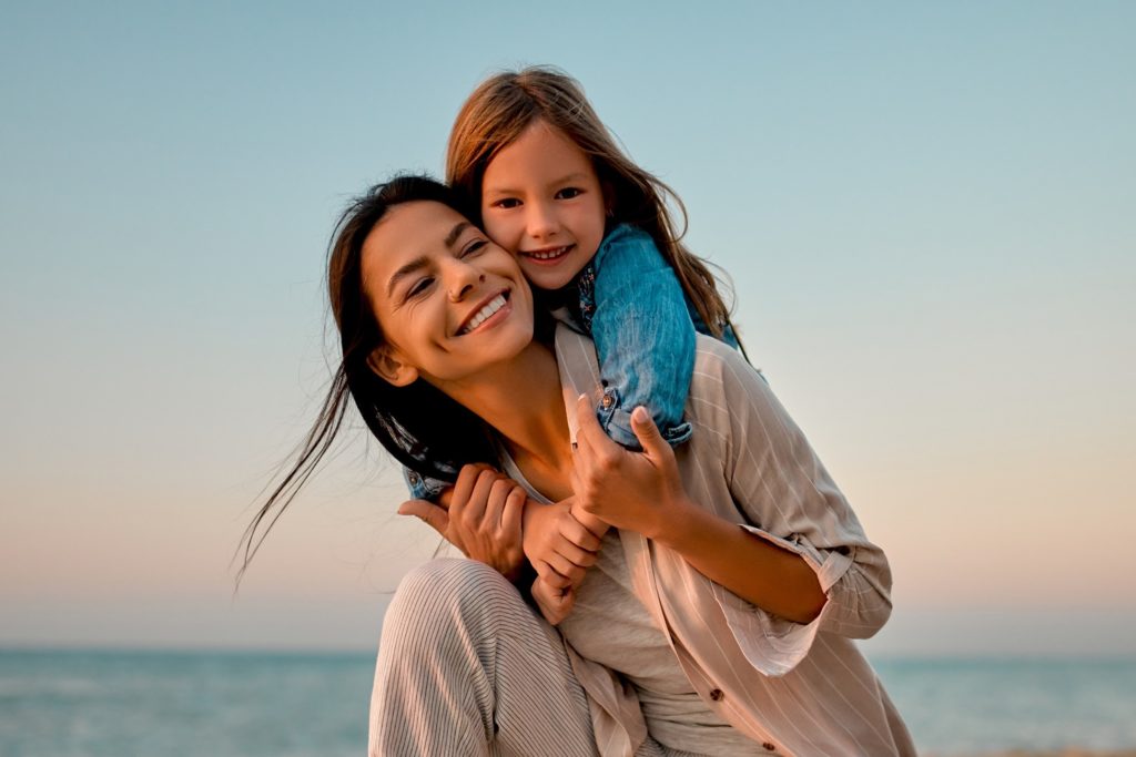 Mom and daughter smiling during summer vacation at beach