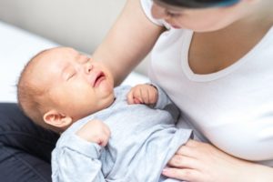 crying baby held by mother